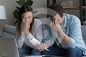Stressed young couple calculating expenses feel upset