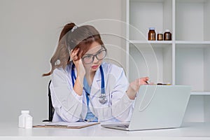 A stressed young female doctor is looking at her laptop and receives bad news about a mistake at work. Feeling tired of