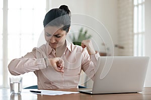 Unhappy millennial woman checking time to workday finish. photo