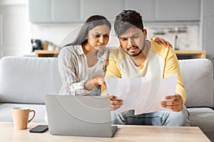 Stressed Young Indian Couple Suffering Financial Crisis Checking Papers At Home