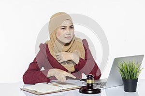 Stressed young lawyer sitting working with her laptop. hand hold