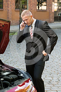 Stressed young man with his breakdown car calling on cellphone