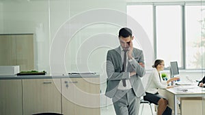 Stressed young man in suit is standing in office waiting for job interview while female interviewer is talking to