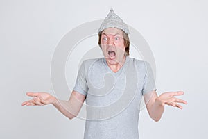Stressed young man with tinfoil hat as conspiracy theory concept looking shocked