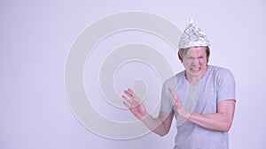 Stressed young man with tinfoil hat touching something and looking scared