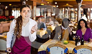 Stressed young waitress fed up with work standing in restaurant