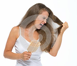 Stressed young woman combing hair