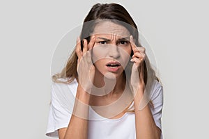 Stressed young woman confused about facial wrinkles looking at camera
