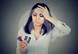 Stressed young woman in debt holding multiple credit cards