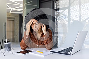 Stressed young woman feeling headache at work desk