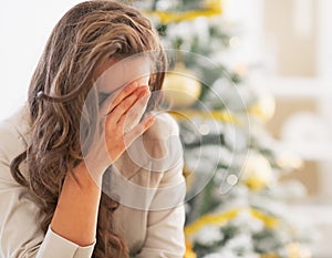 Stressed young woman in front of christmas tree