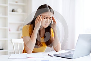 Stressed young woman with headache at computer