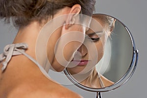 Stressed young woman looking in mirror photo