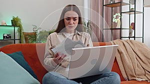 Stressed young woman looking at unpaid bank debt loan, doing paperwork, planning budget throws bills