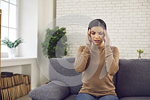 Stressed young woman rubbing her temples, suffering from bad headache or migraine