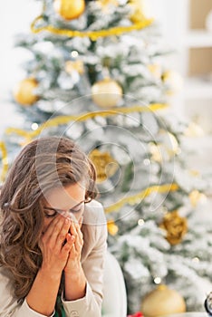 Stressed young woman sitting in front of christmas tree