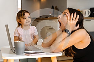 Stressed young woman working from home with small child. Home office of single mother photo