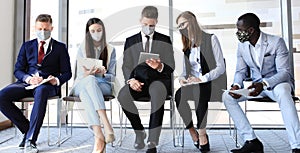 Stressful business people waiting for job interview with face mask, social distancing quarantine during COVID19 affect