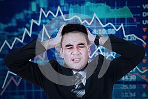 Stressful businessman with stock exchange background