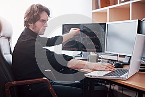 Stressful day at the office. Young businessman holding hands on his face while sitting at the desk in creative office