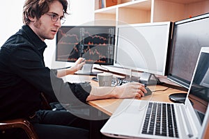 Stressful day at the office. Young businessman holding hands on his face while sitting at the desk in creative office