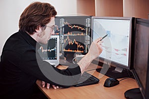 Stressful day at the office. Young businessman holding hands on his face while sitting at the desk in creative office