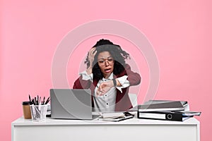 Stressful deadline. Scared woman checking time on wristwatch at white desk against pink background