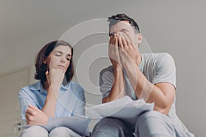 Stressful family couple have debt problems, not able to pay their loan, manage domestic budget, study paper documents, pose