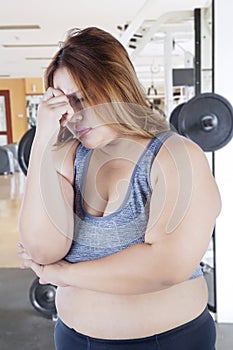 Stressful fat woman standing in the gym center