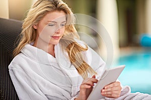 Stressless surfing at the spa. a young woman relaxing with her digital tablet at a day spa.