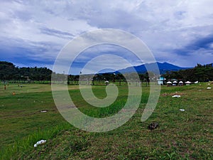 a stretch of green field with very cloudy weather