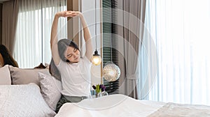 Stretch oneself, Beautiful Asian woman waking up in the morning in her modern bedroom in her new home