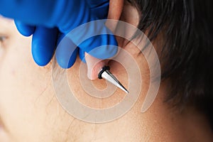Stretching ears for larger diameter tunnels,piercer hand inserts the piercing in the ear