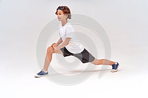 Stretching exercises. Full length of caucasian sporty teenage boy in sportswear warming up before training, standing