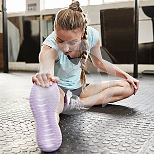 Stretching, fitness and woman in gym for exercise, training and warm up on floor for workout. Health, sports and female