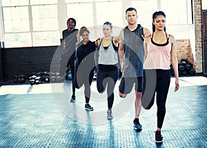 Stretching is important. a focused group of young people standing in a row and stretching before a workout session in a