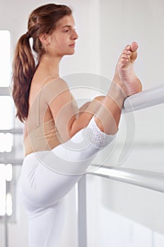 Stretching legs, ballet and girl on barre in studio, practice and student exercise. Ballerina, young teenager and