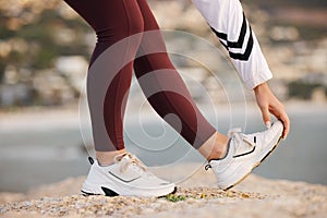 Stretching, legs and woman on a beach rock, start fitness and yoga exercise in nature of Portugal. Warm up, training and