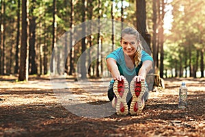 Stretching is the most important part. Shot of a sporty young woman doing stretch exercise while out in nature.