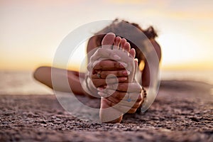 Stretching, peace and feet of a woman on beach for yoga, training and exercise during sunset. Fitness, sand and legs of