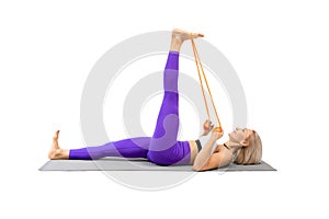 Stretching with resistance band. Caucasian fit woman lying on back and pull a straight banded leg towards her, isolated