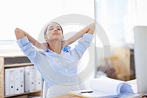 Stretching those tight neck muscles. Shot of young businesswoman taking a moment to relax at her desk.