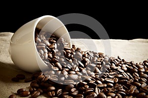 Strewn beans of coffee from a cup on black and flax photo