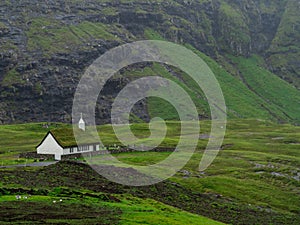Streymoy, Saksun. View on Saksun`s church and valley. White building with grass roof standing out of the green