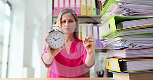 Strict authoritative boss holding alarm clock at desk