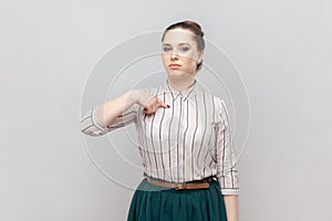 Strict bossy serious woman standing pointing at herself with proud expression, looks arrogant.