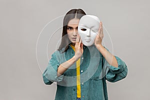 Strict bossy woman covering half of face with white mask, multiple personality disorder.