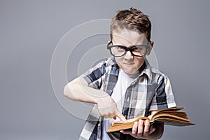 Strict boy in glasses with book in hands,