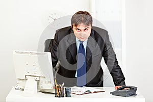 Strict businessman standing at office desk