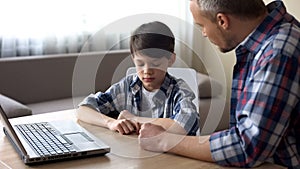 Strict father scolding his little son for computer addiction, family problem